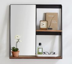 a mirror sitting on top of a wooden shelf next to a plant and a clock