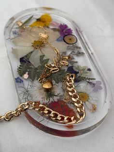 a clear case with flowers and gold chains on the bottom is holding a keychain