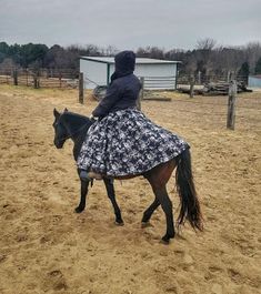 a woman riding on the back of a brown horse in a fenced in area