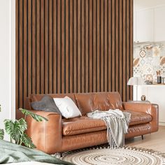 a brown leather couch sitting on top of a rug in front of a wooden wall