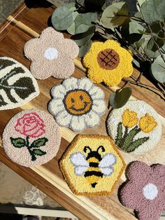 four coasters with flowers and bees on them sitting on a wooden table next to a potted plant