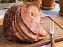 a large piece of meat sitting on top of a cutting board next to potted plants