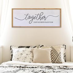 a bed with pillows and a wooden sign above it that says together is my favorite place to be