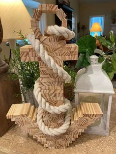 an anchor made out of wood and rope sitting on top of a table next to a lantern