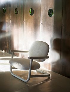 a white chair sitting in front of a metal wall