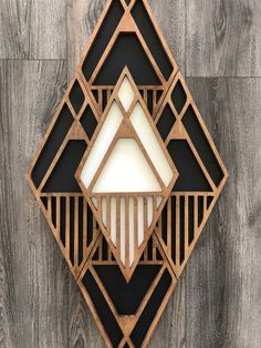 an art deco wall hanging on the side of a wood paneled wall with white and black geometric shapes