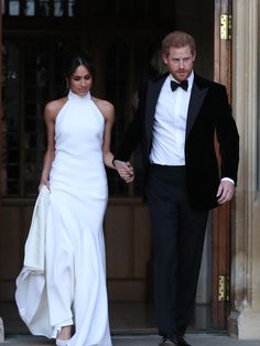 a man and woman in formal wear walking out of a building holding hands with each other