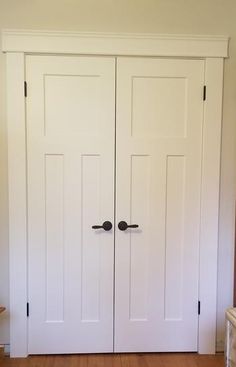 two white closet doors with black handles and knobs in a home entryway area