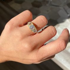 a person's hand with a diamond ring on top of their finger and the other hand holding an object