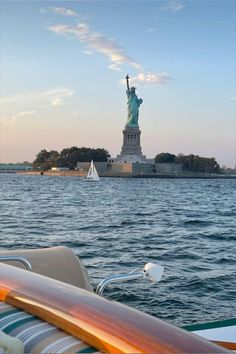 the statue of liberty is seen from across the water with sailboats in the foreground