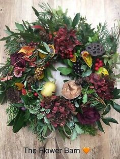 a wreath is sitting on the floor with leaves and flowers around it, surrounded by other decorations