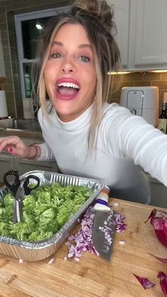 a woman is cutting lettuce in the kitchen and making funny faces for the camera