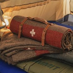 two blankets folded on top of each other in front of a tent with a lamp