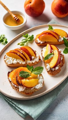 slices of bread with peaches and goat cheese on them sitting on a white plate