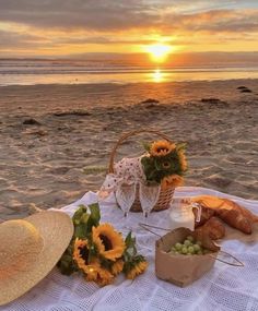 a picnic on the beach with sunflowers, bread and wine in front of it