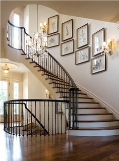 a staircase with pictures on the wall and chandelier