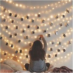 a woman standing in front of a string of lights with polaroid frames on it