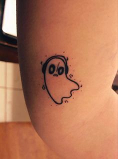 a woman's leg with a ghost tattoo on it