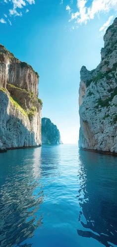 the water is calm and blue with cliffs in the background