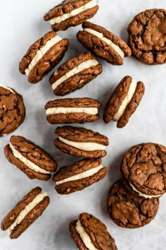 chocolate cookies with white frosting are arranged on a marble counter top, next to each other