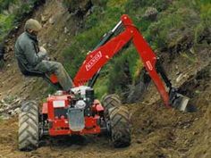 a man sitting on top of a red tractor next to a pile of dirt and grass