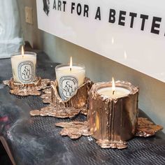 three candles sitting on top of a table next to a sign that says art for a better