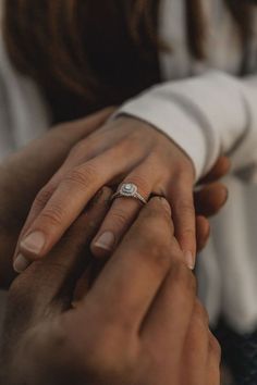 two people holding each other's hands while they hold their wedding rings in their hands