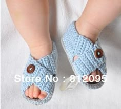 a close up of a baby's feet wearing blue crocheted slippers