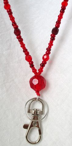 Red Beaded Lanyard This Red Beaded Lanyard can be used as a badge holder, an I.D. holder, keychain necklace, watch holder - it's a multi-use accessory for home or office! 34" in length, long enough to put on or remove overhead. It also has an easy-to-use metal lobster clasp for your convenience. It's made with red glass beads and strung on strong C-Lon beading cord. Snap-on badge holder, clip, and keyring are included to keep your badges or keys ready when you need them. This Red Beaded Lanyard Adjustable Red Lanyard With Key Leash, Red Lanyards With Key Leash, Adjustable Red Lanyard As Gift, Red Lanyard With Key Leash As Gift, Red Lanyards With Key Leash For Gifts, Keychain Necklace, Lanyard Necklace, Beaded Lanyard, Beading Cord