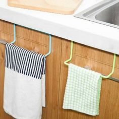 two towels hanging on the kitchen wall next to a sink with a wooden cutting board