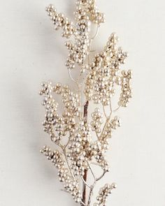 a brooch with pearls on it sitting on top of a white table next to a plant