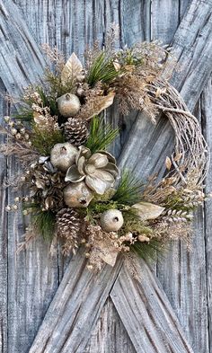 a wreath made out of branches and pine cones on a wooden door with other decorations