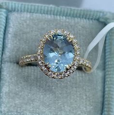 an oval blue topaz surrounded by white and yellow diamonds sits in a velvet box