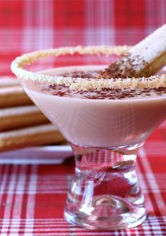 a dessert in a glass on a red tablecloth with some sticks sticking out of it