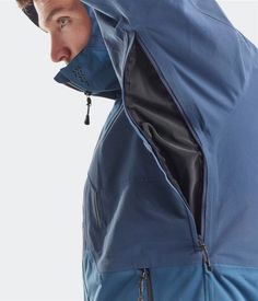 a man wearing a blue jacket and hoodie with his face partially hidden under the hood