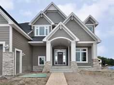 a gray house with white trim and two story windows on the front door is shown