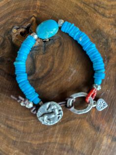 This detailed horse / pony button looks so pretty against these brilliant blue turquoise stones. The center stone is blue turquoise magnesite. The pony button, with the pony in raised relief, is pewter that has been finished to look like oxidized Sterling Silver. All the other silver in this bracelet is .925 Sterling. The loop has hand stamped designs and the sterling heart charm has a tiny hallmark on its reverse side. 7 and 1/2 inches long. Handmade Western Style Turquoise Bracelet, Handmade Western Turquoise Bracelet, Handmade Western Turquoise Bracelets, Rustic Blue Jewelry For Festival, Blue Bohemian Concho Jewelry, Rustic Blue Adjustable Beaded Bracelets, Rustic Blue Adjustable Beaded Bracelet, Rustic Adjustable Blue Beaded Bracelet, Southwestern Blue Concho Bracelets