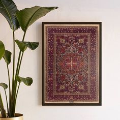 a red rug hanging on the wall next to a potted plant and a gold vase