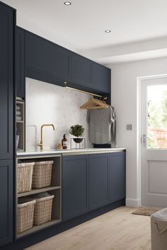 a kitchen with blue cabinets and white walls, an open door to the outside is shown