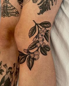 tattoos on the legs of two people, one with berries and an owl in it