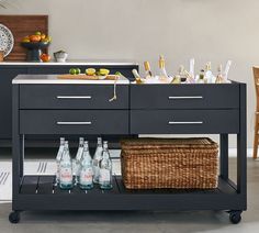 a kitchen cart with bottles and baskets on it in front of a counter top filled with drinks