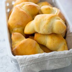 some bread rolls in a white dish on a table