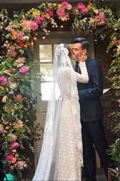 the newly married couple kiss in front of a floral arch