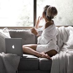 a woman sitting on top of a couch next to a window with palm trees outside