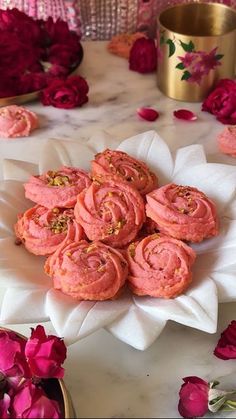 some pink cookies are on a white plate with flowers in the backgroung