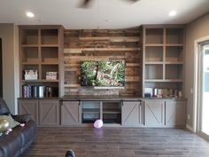 a living room filled with furniture and a flat screen tv on top of a wooden wall