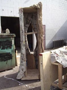 an old wooden cabinet with newspaper covering it's doors and window frame in front of a white brick wall