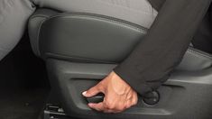 a person is sitting in the back seat of a car with their hand on a remote control