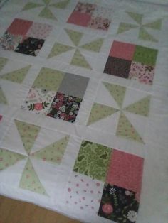 a quilted table topper with many different colored squares on it, including pink and green