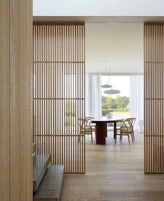 an open door leading to a dining room with wooden slats on the walls and floor